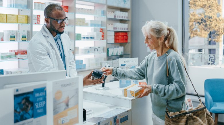 femme payant ses médicaments à la pharmacie