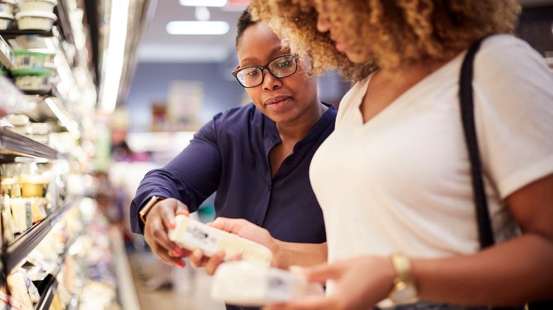 deux femmes regardent les étiquettes nutritionnelles du fromage