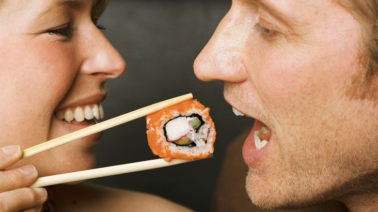 femme donnant à manger à un homme un rouleau de sushi