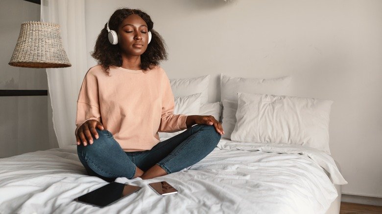 femme méditant sur le lit avec des écouteurs