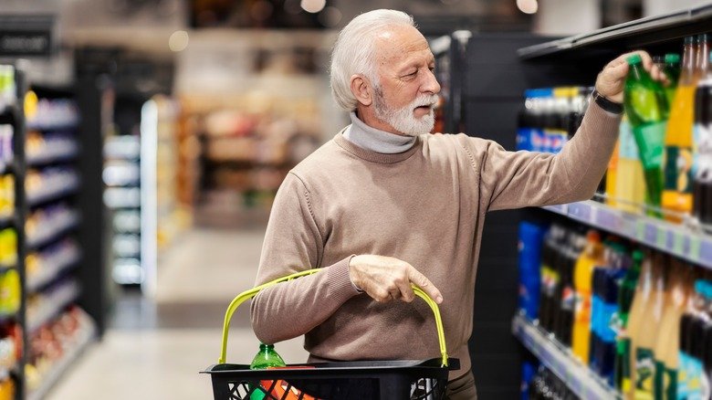 Un homme âgé fait ses courses dans le rayon des boissons 