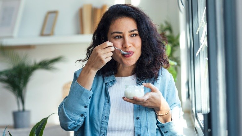 Femme souriante mangeant une cuillerée de yaourt