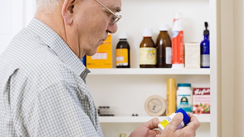 Homme regardant dans une armoire à pharmacie