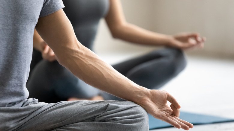 Gros plan des mains de deux personnes dans un cours de yoga