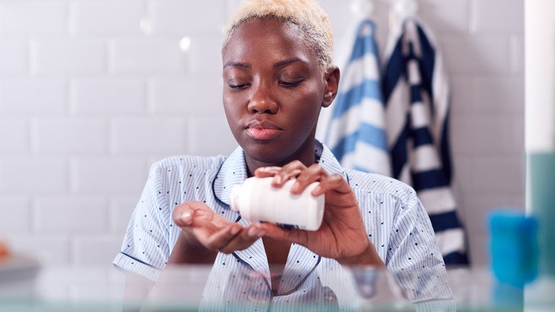 Femme prenant des médicaments dans la salle de bain