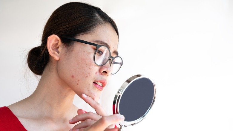 femme examinant son visage dans un miroir