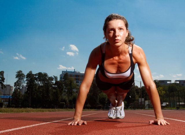 femme en forme faisant des pompes ou des planches sur piste, concept d'entraînement au poids du corps pour les bras flasques