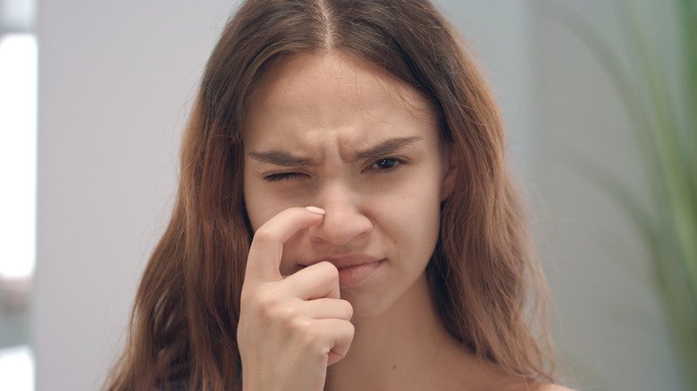 Une femme se gratte le côté du nez