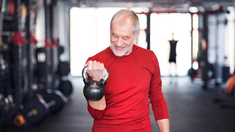 homme plus âgé faisant des curlings avec une kettlebell