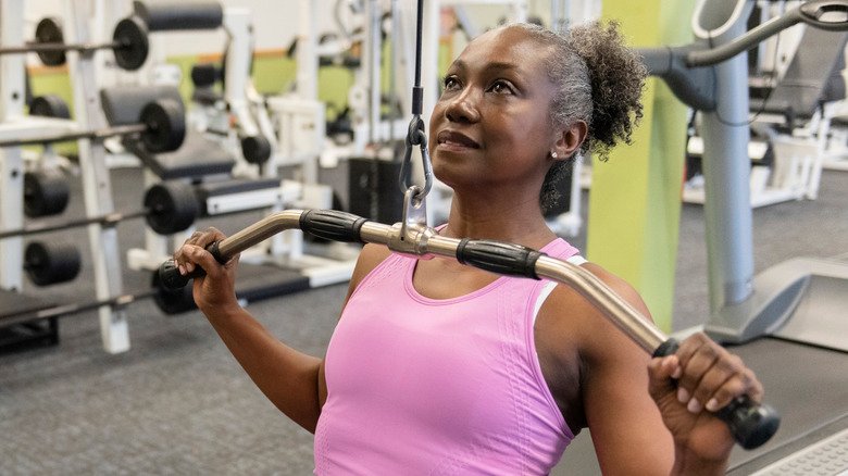 femme âgée faisant des tirages latéraux à la salle de sport