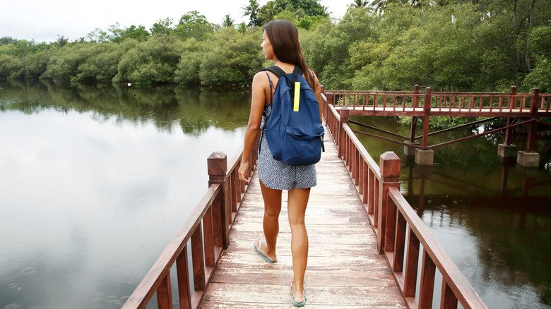 femme portant un sac à dos traversant une passerelle piétonne