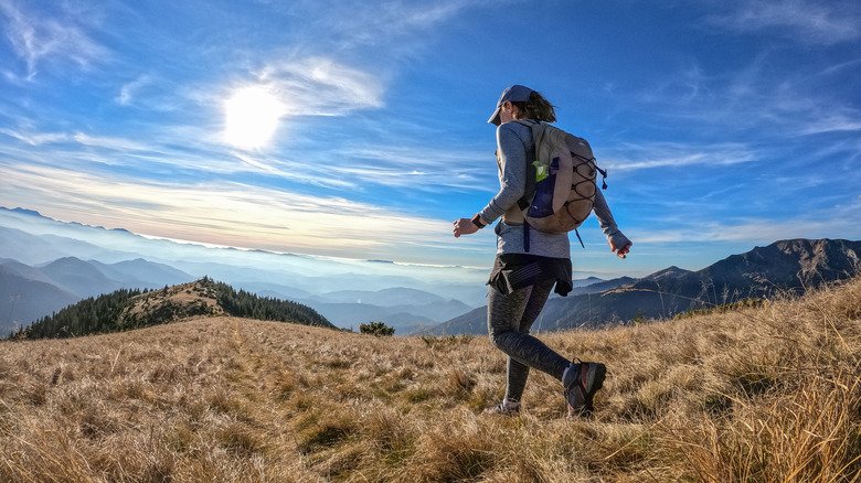 femme marchant avec un sac à dos avec des montagnes à l'horizon