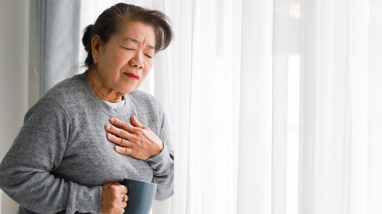 Femme tenant sa main sur sa poitrine en raison de la douleur