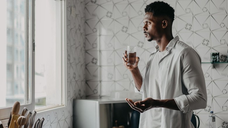 Homme tenant des médicaments et un verre d'eau