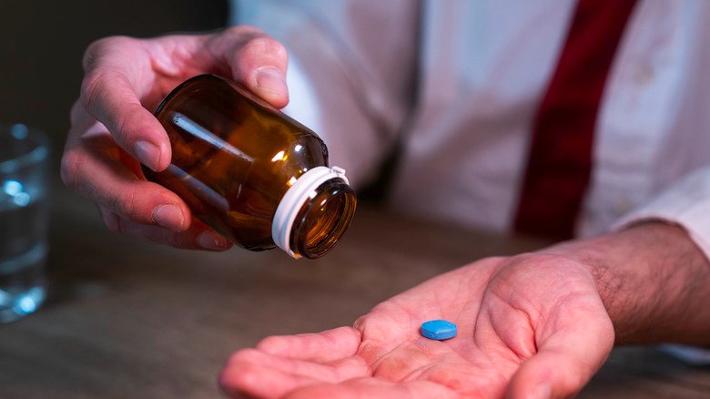 un homme met un comprimé de Viagra dans sa main