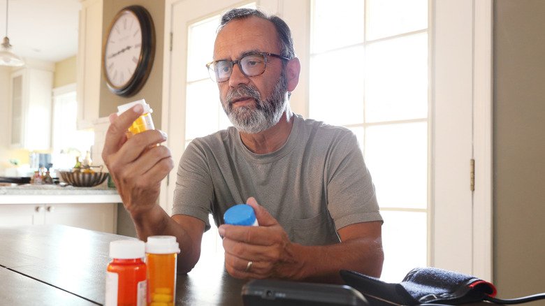 homme plus âgé regardant une bouteille de médicaments