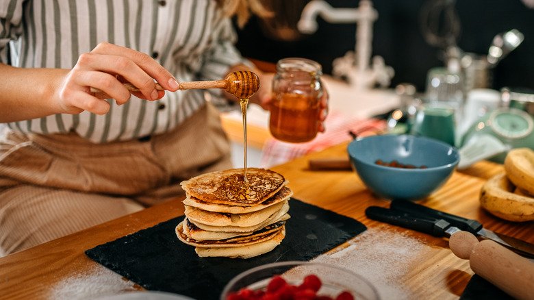 femme ajoutant du miel aux crêpes