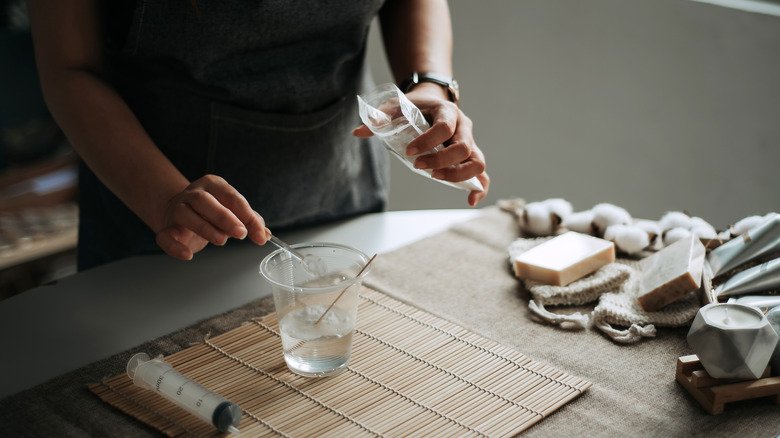 femme versant du bicarbonate de soude dans un verre d'eau