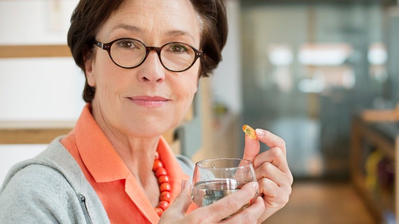 femme âgée prenant un supplément avec de l'eau