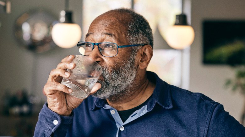 homme barbu à lunettes buvant de l'eau