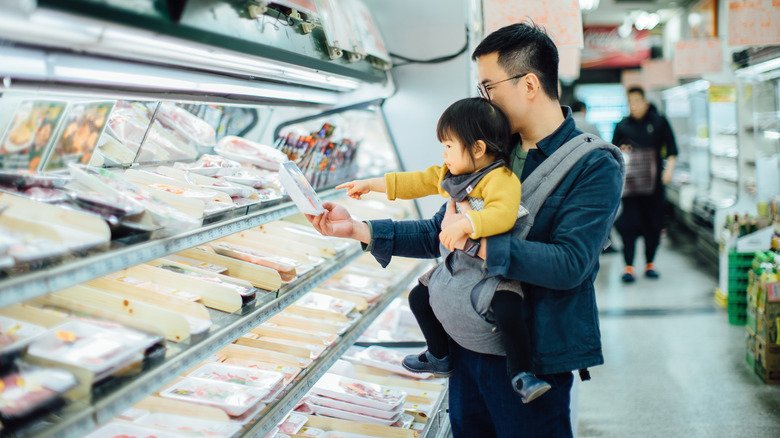 père et fille choisissant des morceaux de poulet au magasin