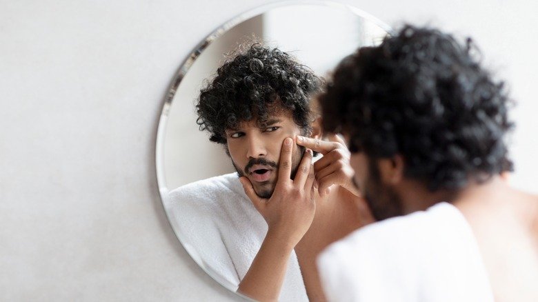 homme inspectant un bouton dans un miroir