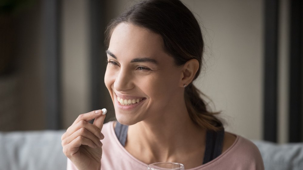 femme souriante prenant un supplément avec de l'eau 