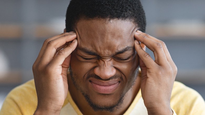 homme tenant la tête avec douleur