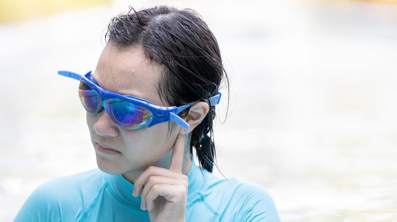 Jeune femme tirant sur son oreille dans la piscine