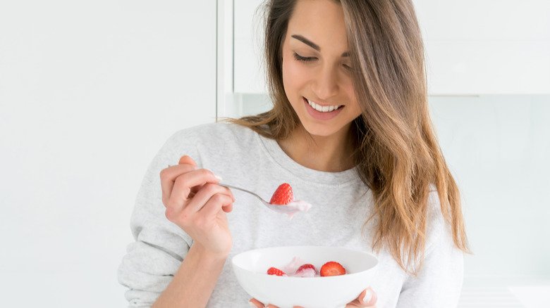 femme mangeant du yaourt nature avec des fruits