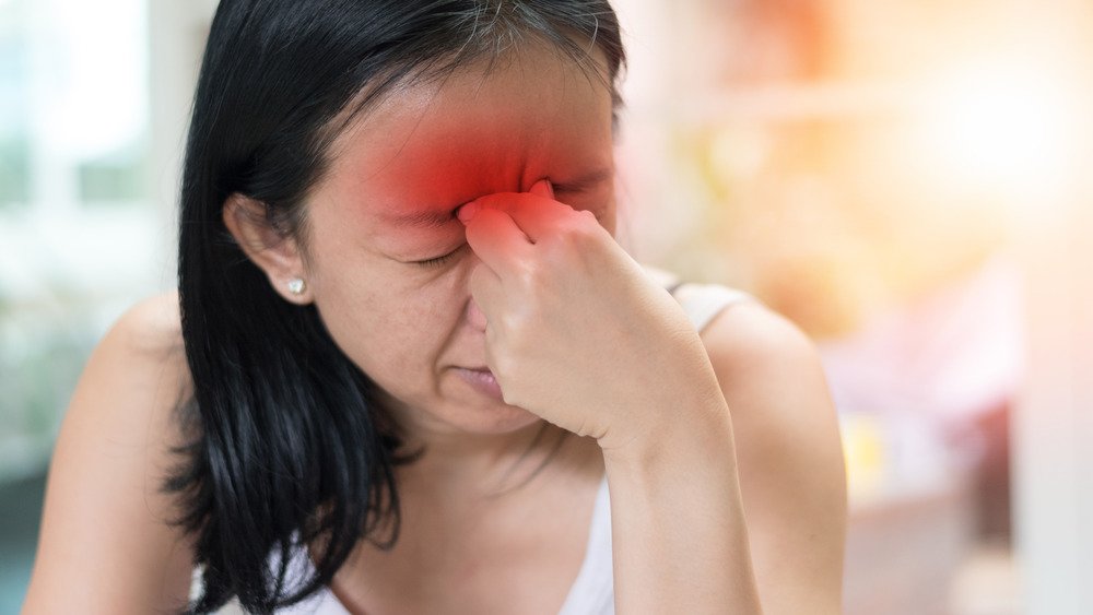 Femme se pinçant l'arête du nez en raison de douleurs aux sinus