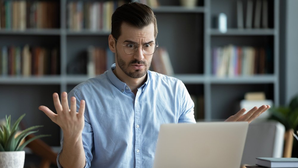 Un homme confus regarde son ordinateur et haussa les épaules