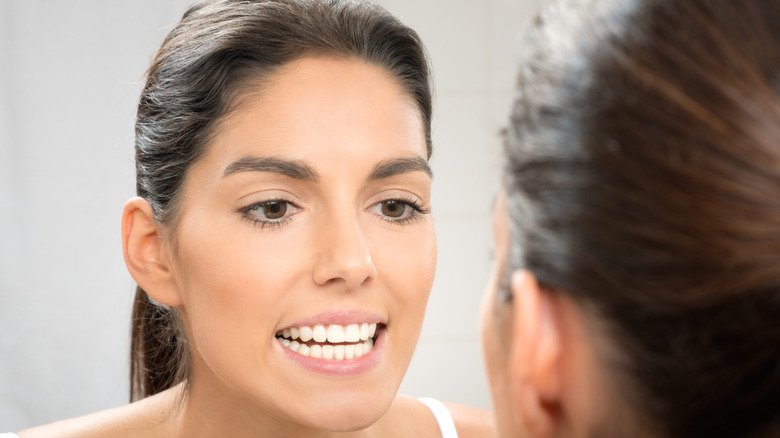 Une femme vérifie ses dents dans le miroir