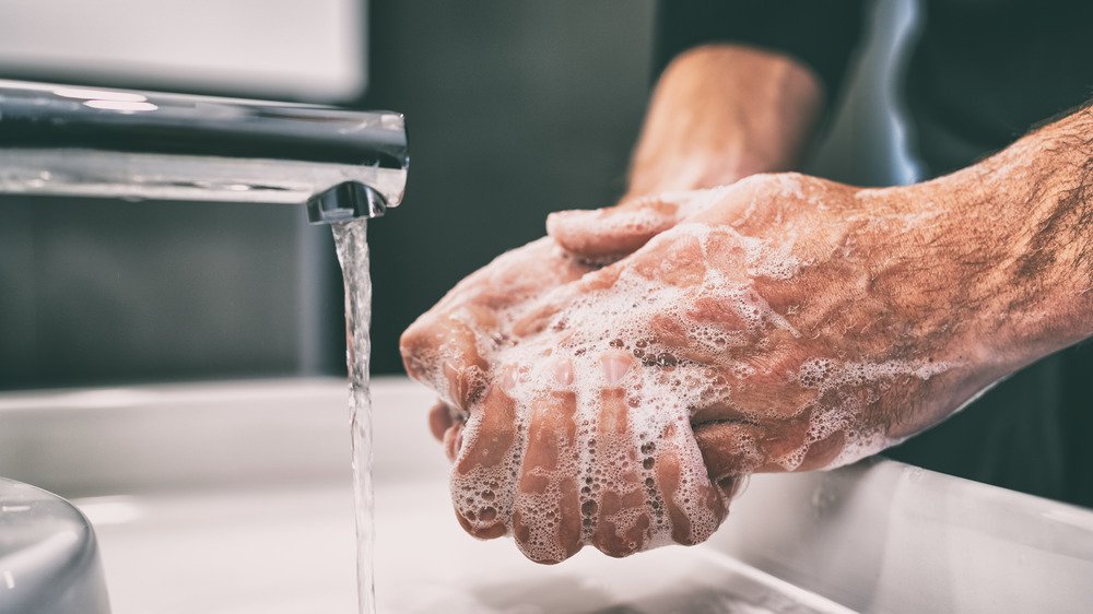 Un homme se lave les mains avec de l'eau chaude savonneuse