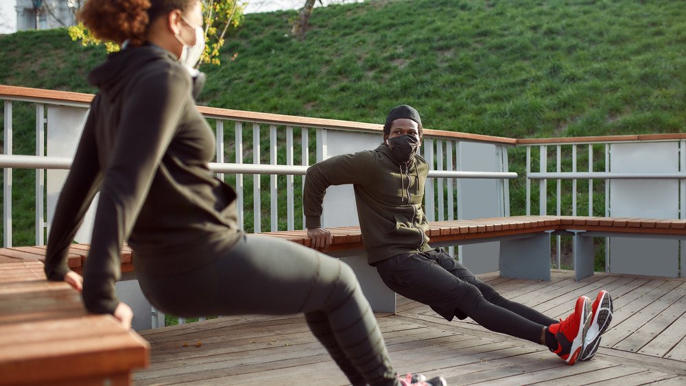 couple faisant des exercices à l'extérieur avec des masques