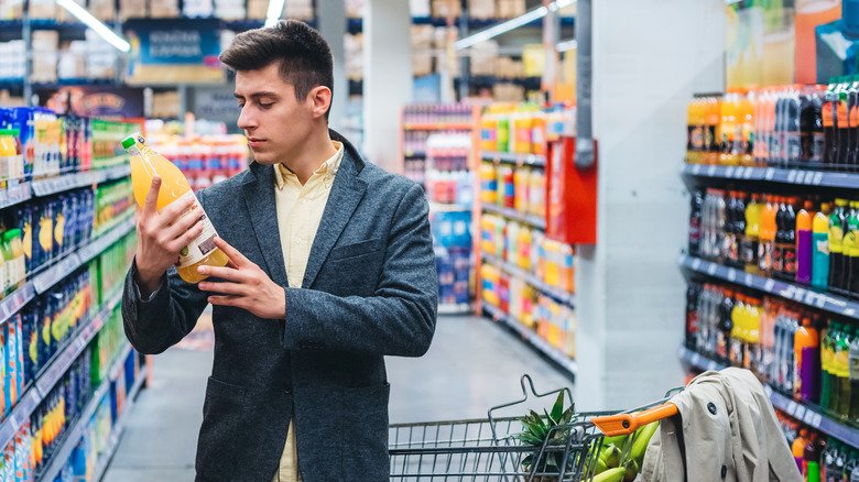 Un homme fait ses courses dans l'allée des boissons d'un magasin