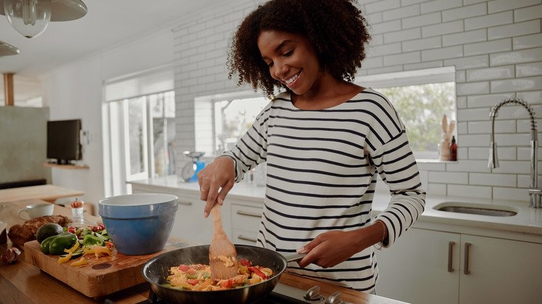 femme préparant un sauté riche en fibres avec des légumes