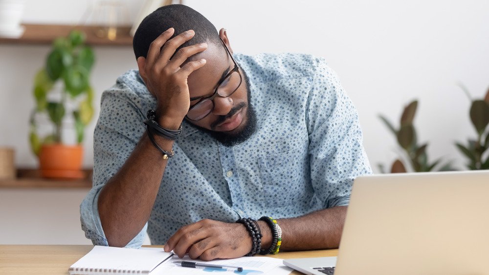 Un homme se tient la tête au bureau