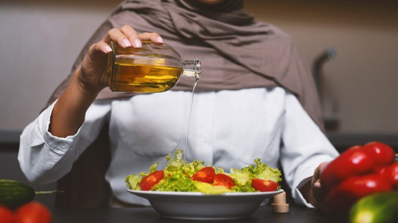 Femme versant de l'huile sur une salade