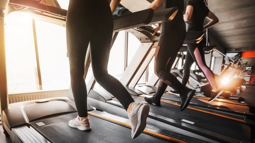 une rangée de personnes courant sur des tapis roulants dans une salle de sport 