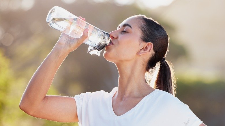 Une femme boit de l'eau à l'extérieur