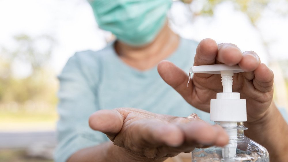 homme portant un masque et utilisant un désinfectant pour les mains