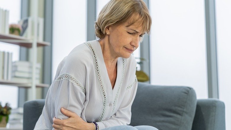 Femme souffrante assise sur un canapé