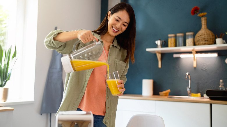 Femme versant du jus d'orange dans un verre