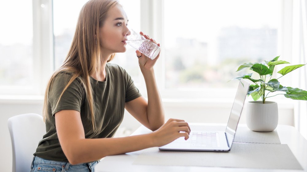 femme buvant de l'eau au bureau