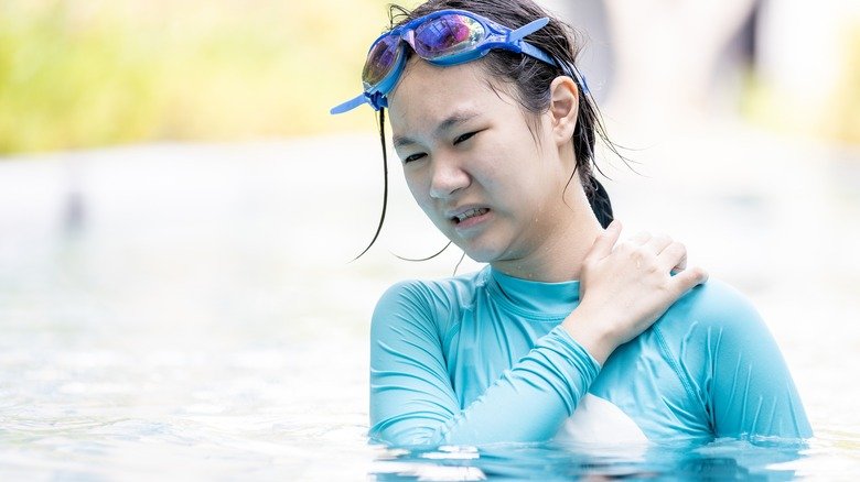 Jeune femme se grattant la peau dans la piscine