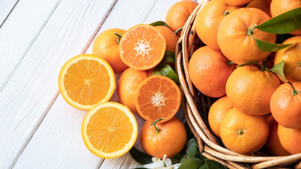 Variétés d'oranges aux feuilles vertes sur une table en bois blanc