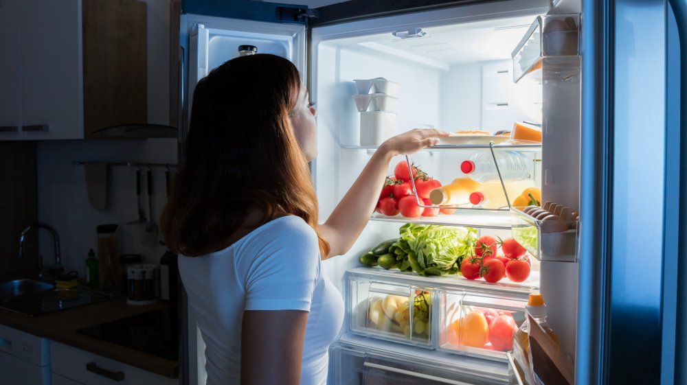 femme regardant dans le réfrigérateur la nuit