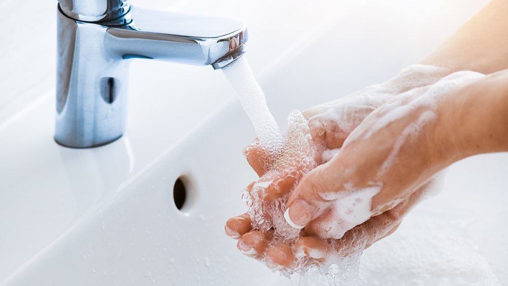 La femme utilise du savon et se lave les mains sous l'eau