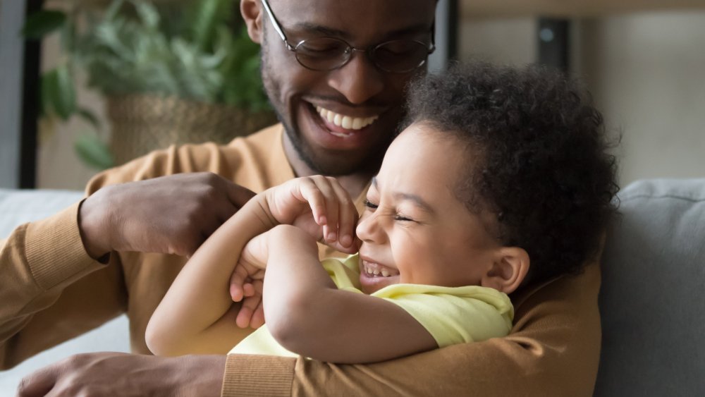 Un père chatouille son jeune fils